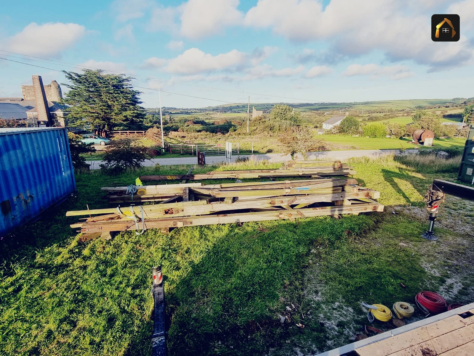 Reclaimed timber beams from the dismantled mine headframe stacked in a Cornish valley