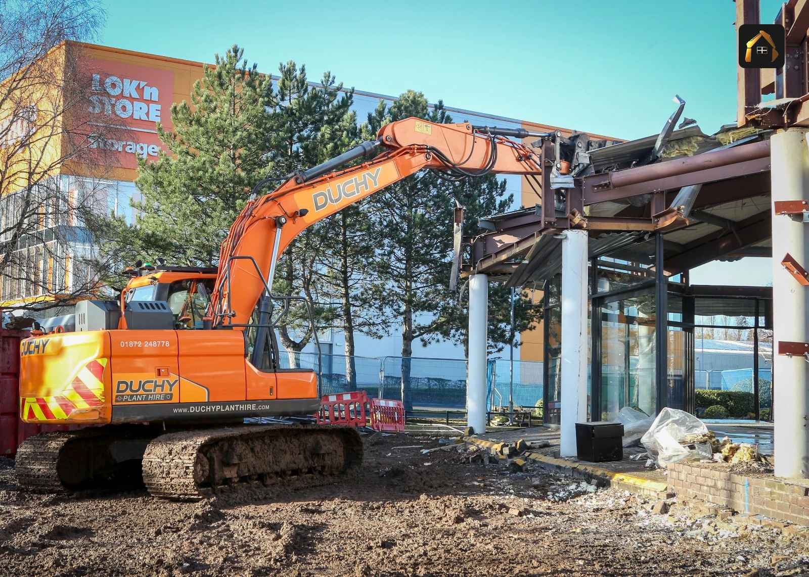 Excavator with a sorting grab dismantling the BMW showroom frontage in Exeter