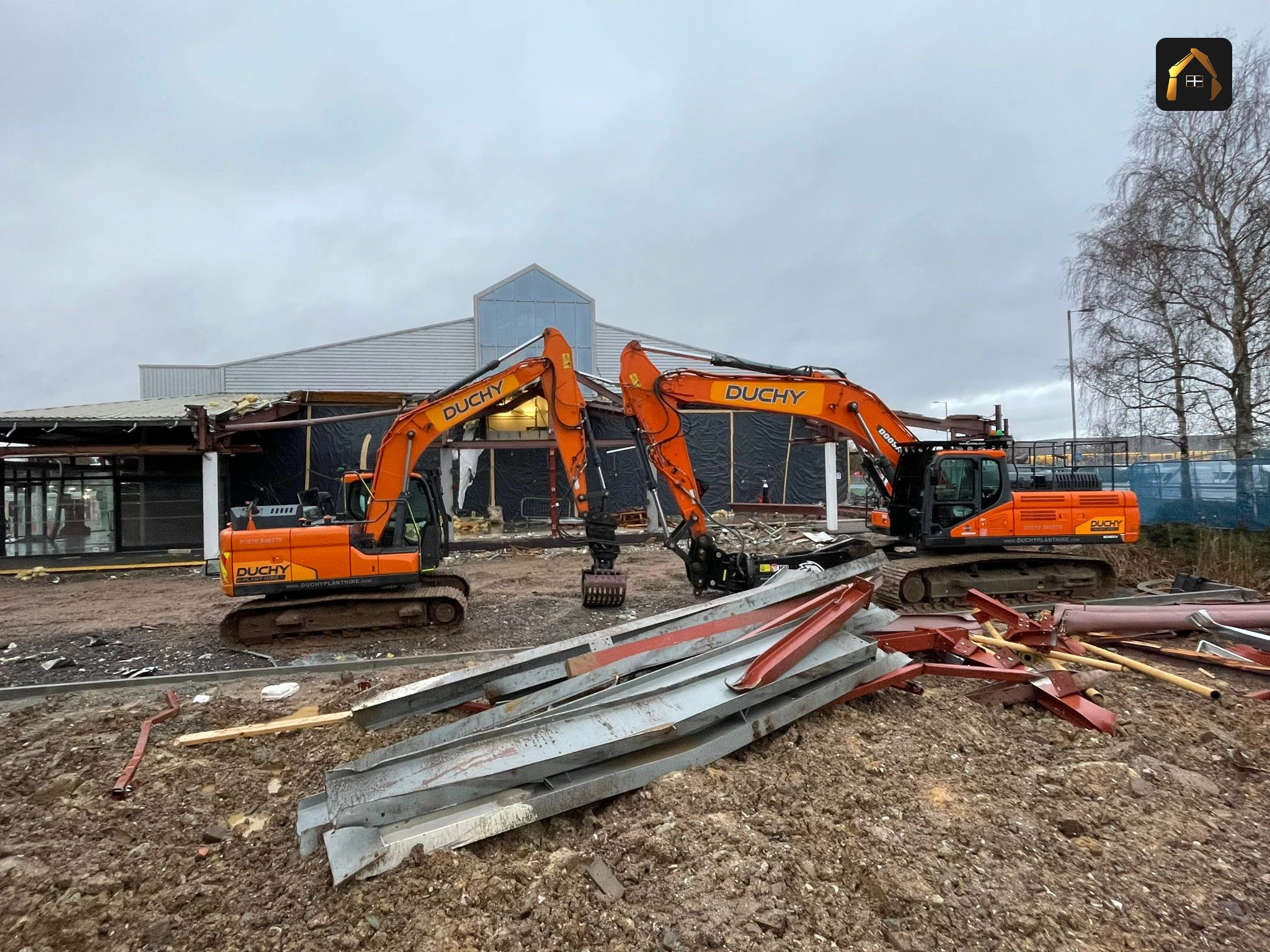 Two excavators and stacked steel on the cleared dealership site in Exeter