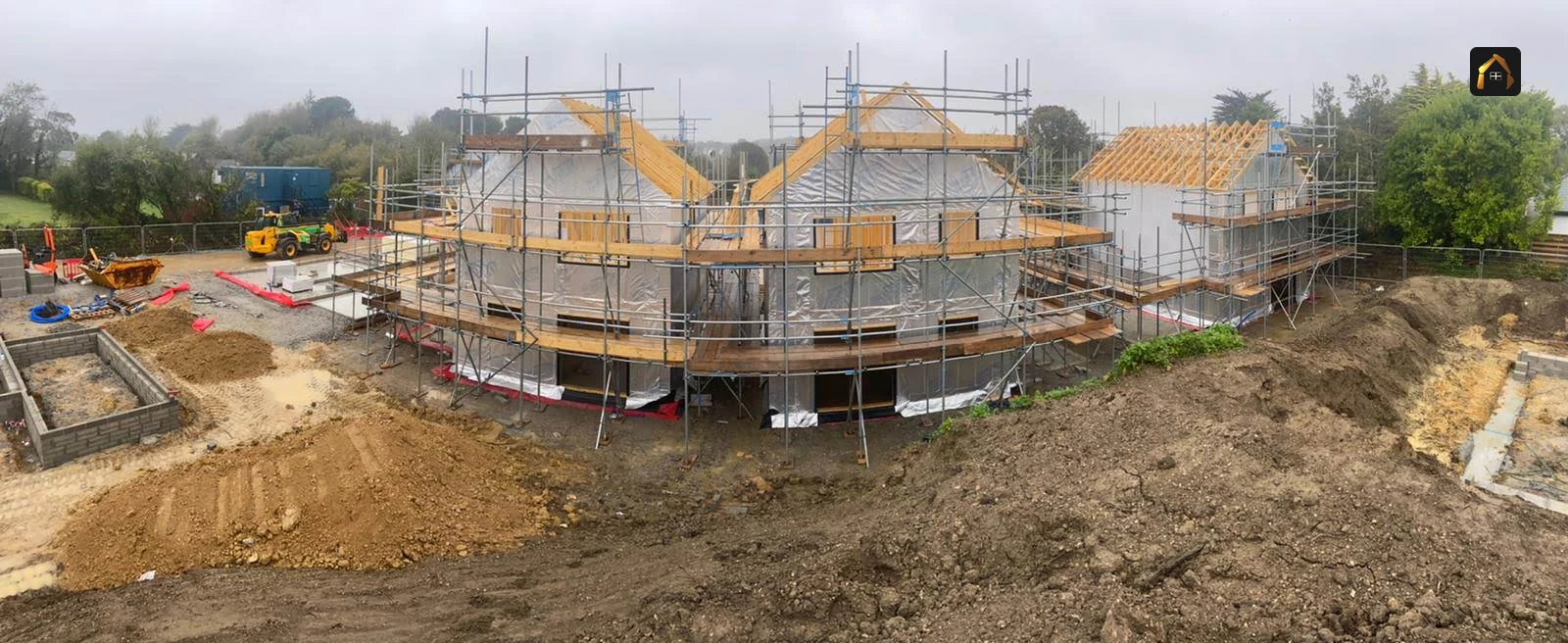 Scaffolded new houses behind open groundworks in Goonhavern