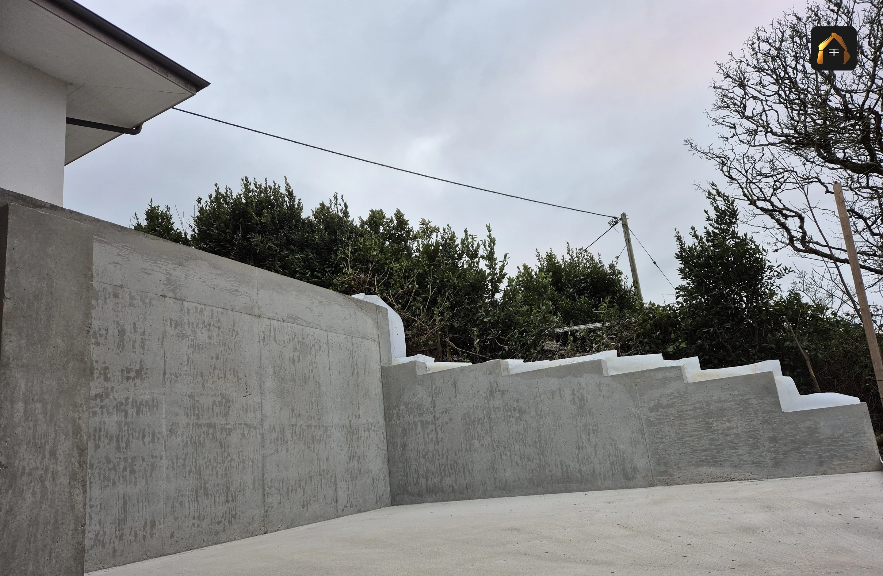 Completed stepped reinforced concrete retaining wall along the full length of the plot in Helford