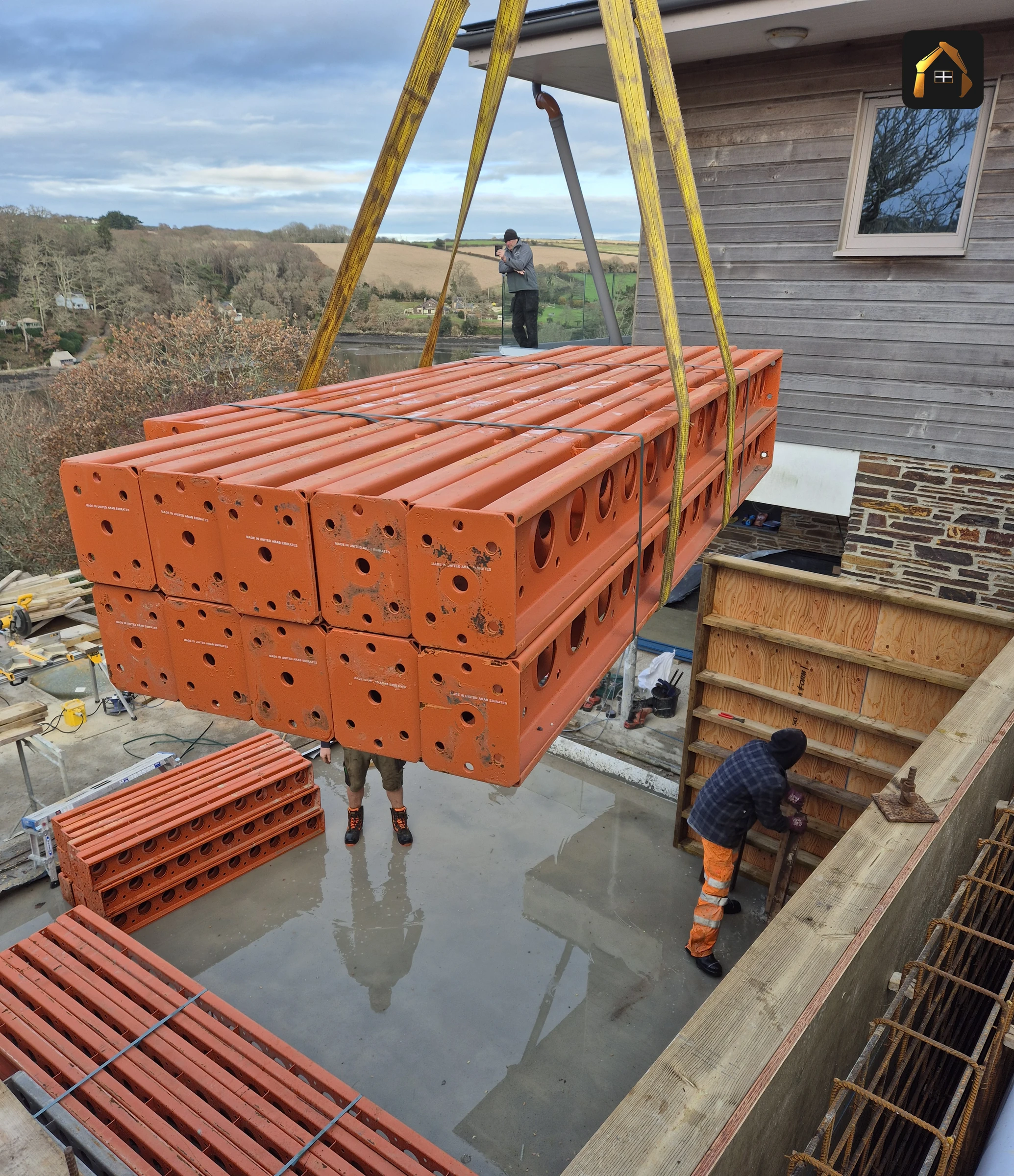 Orange modular formwork lifted into place by excavator in Helford