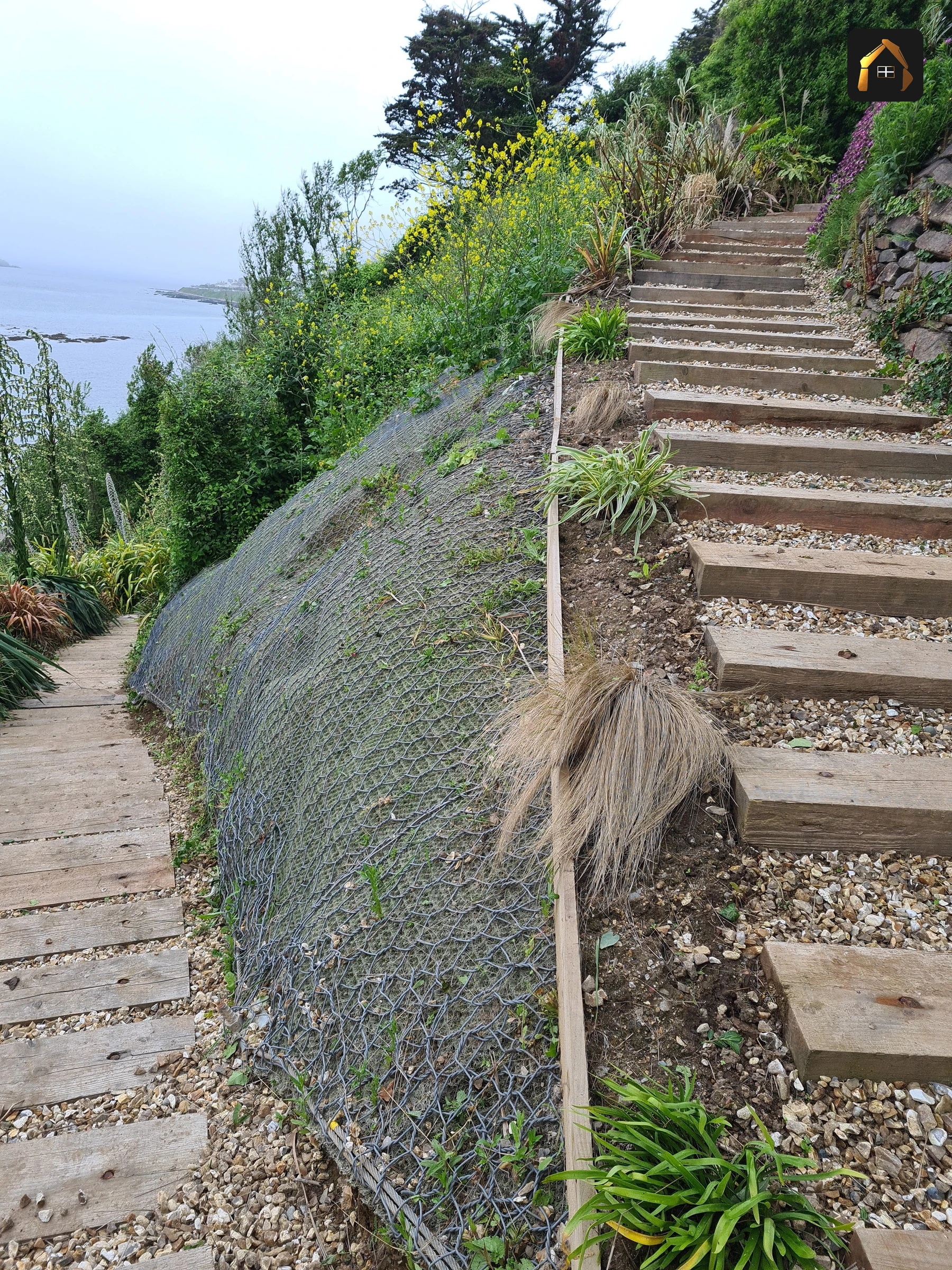Erosion control matting pinned across a steep cliff face in Looe