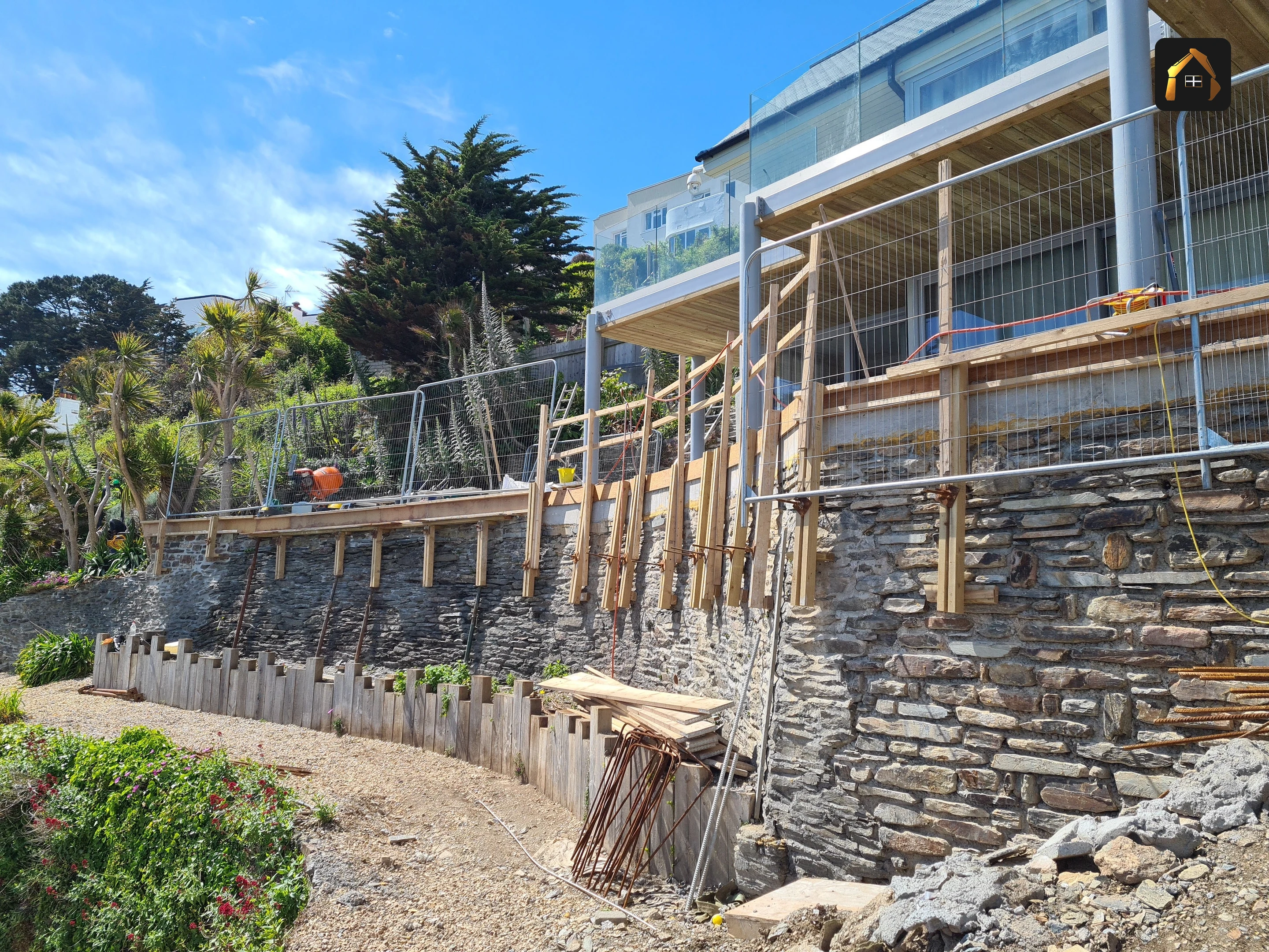 King post timber retaining wall seen from below with the house above in Looe