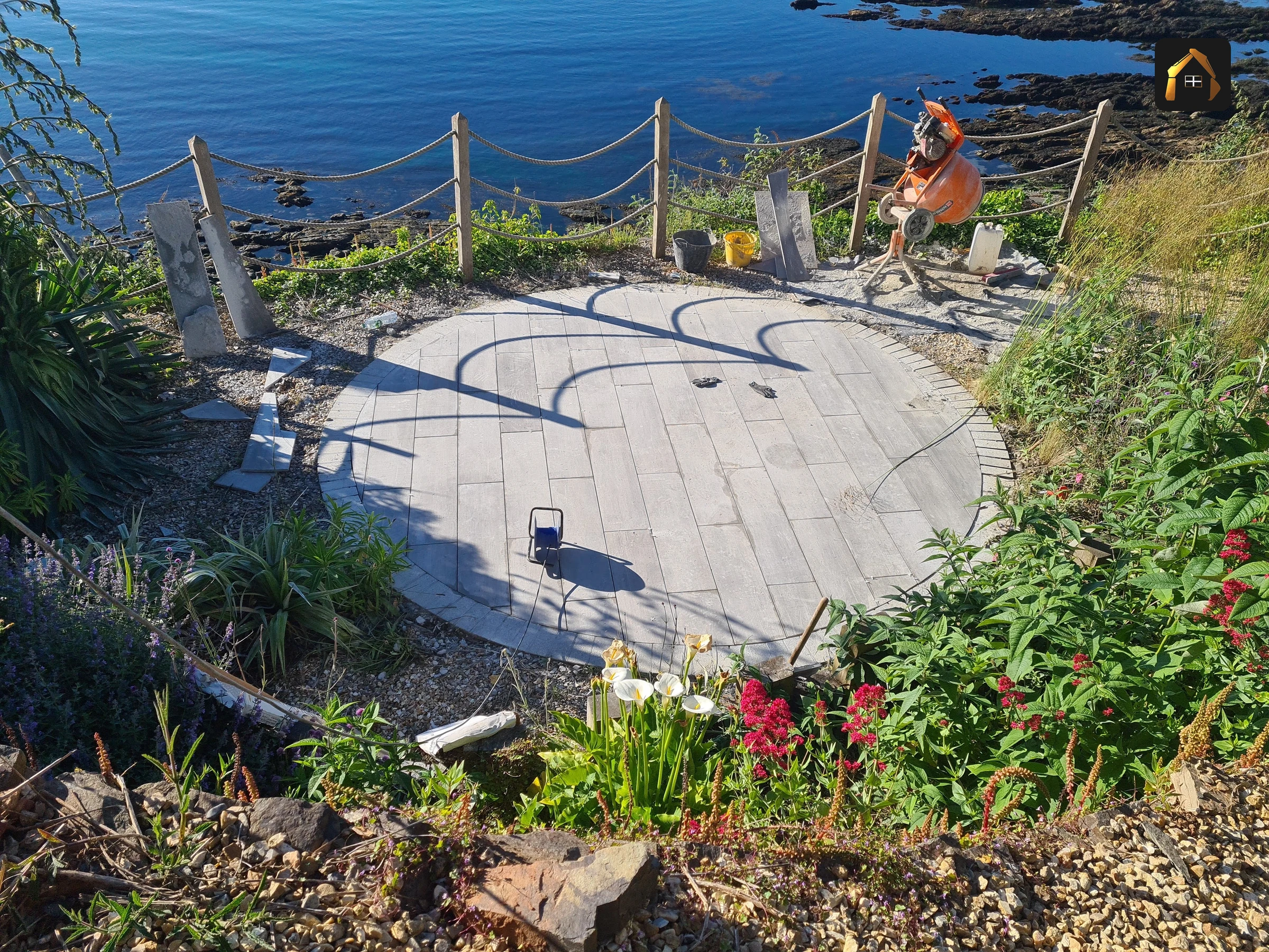 Completed stone circle terrace with coastal grass and the sea in Looe