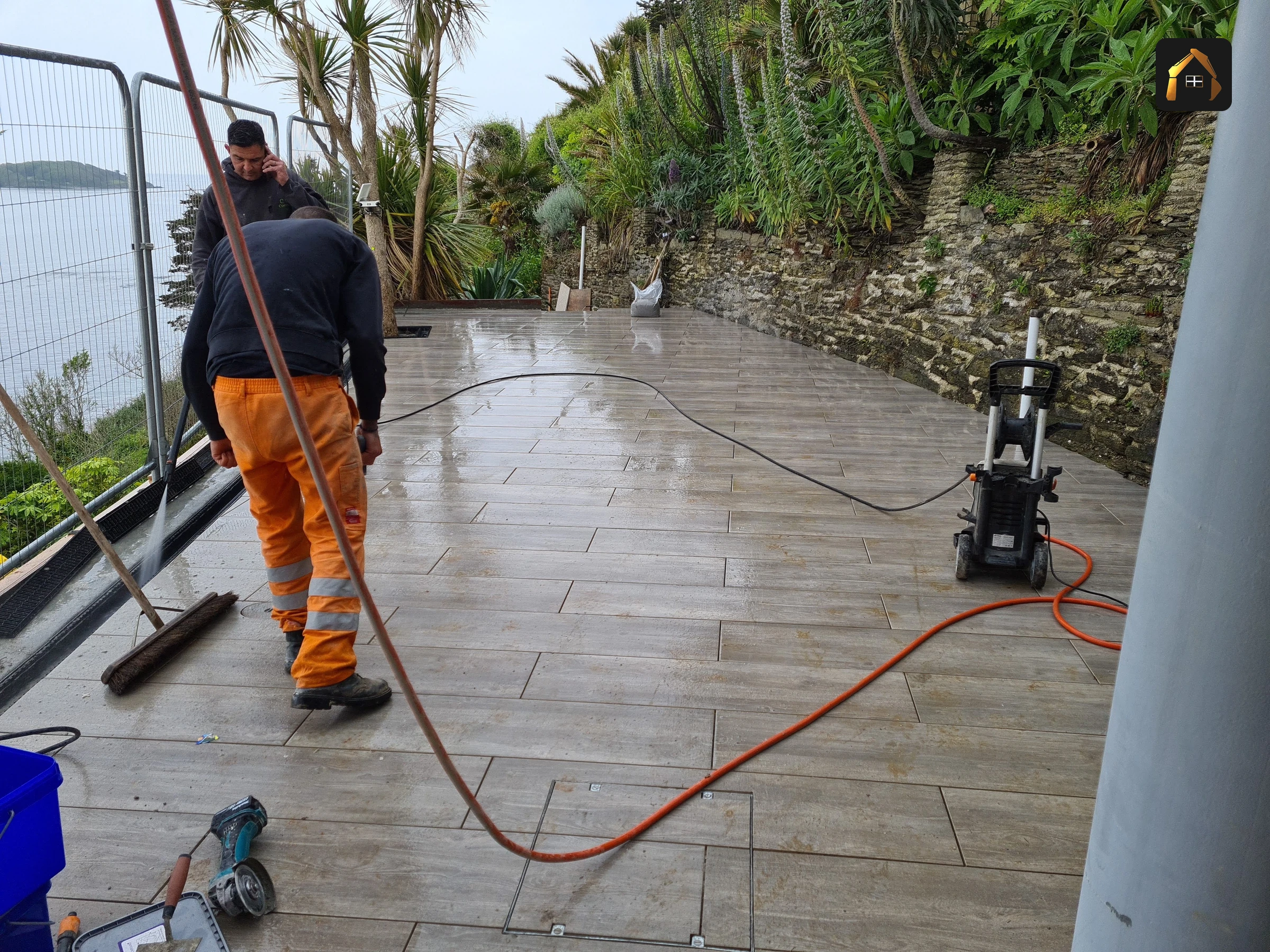 Worker jet washing finished stone paving in Looe