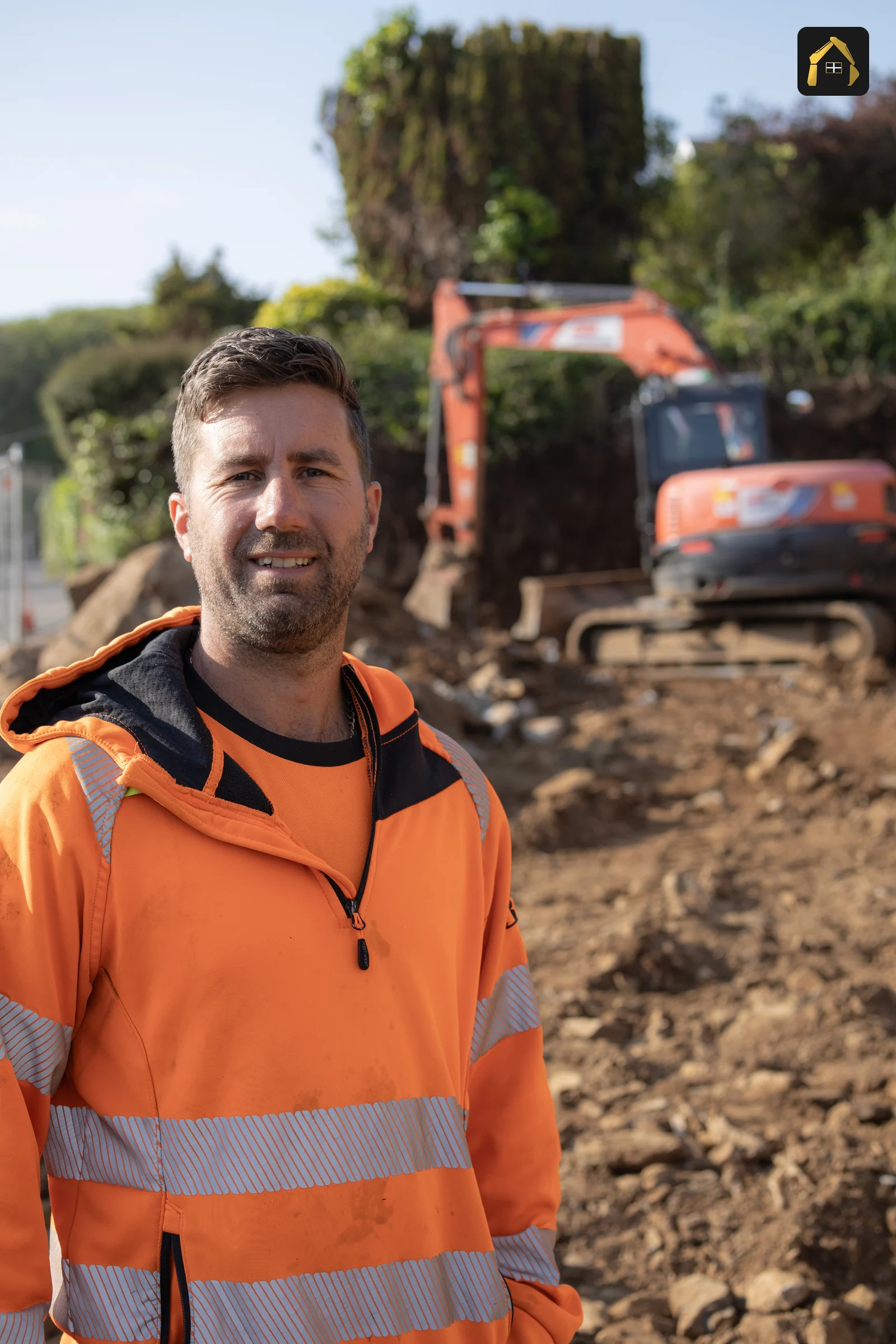 Matt Richards, director of Cornwall Civils & Construction, on site in hi-vis with his excavator behind him