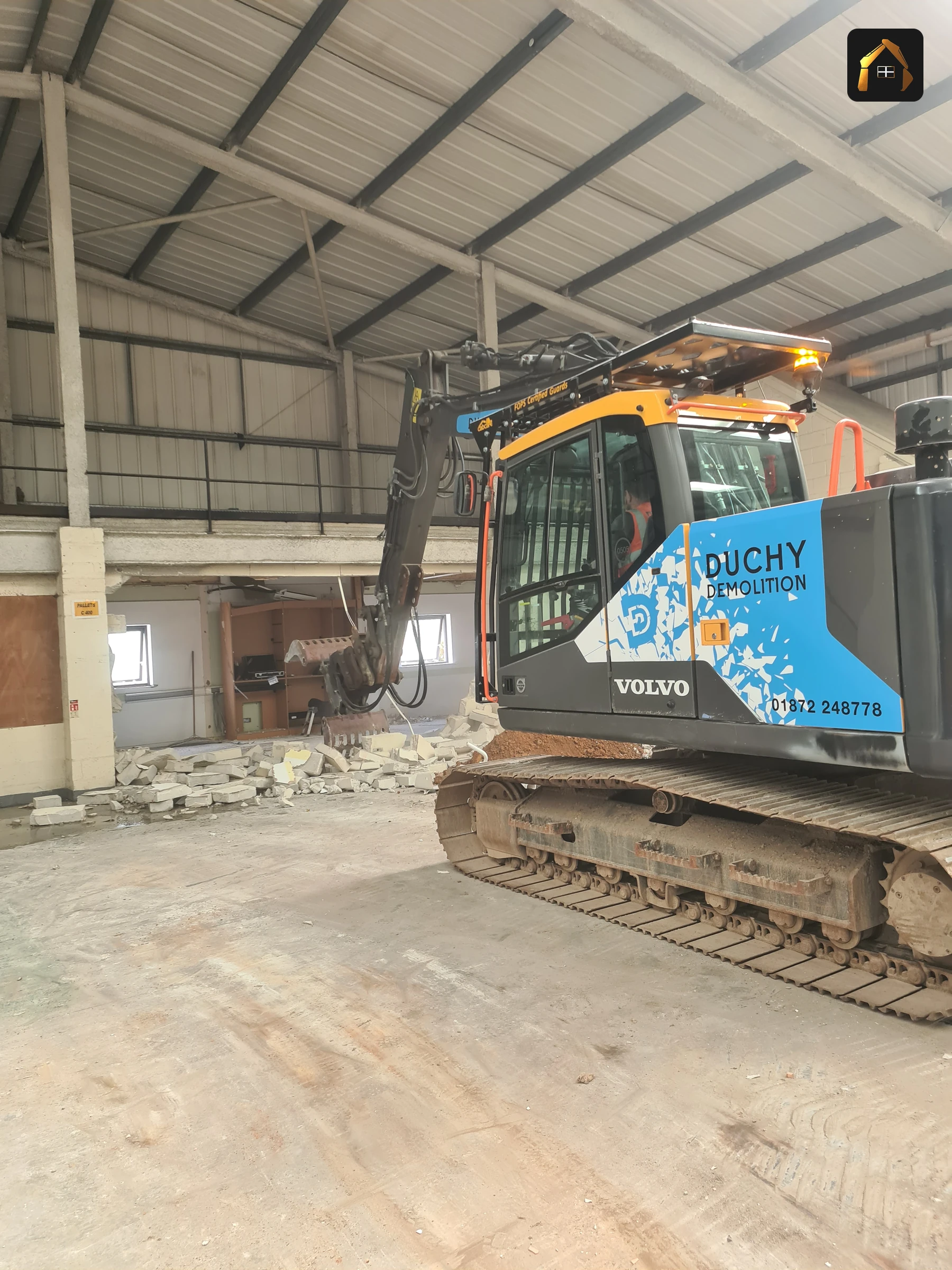 Tracked excavator inside the stripped Fal Fish warehouse in Redruth