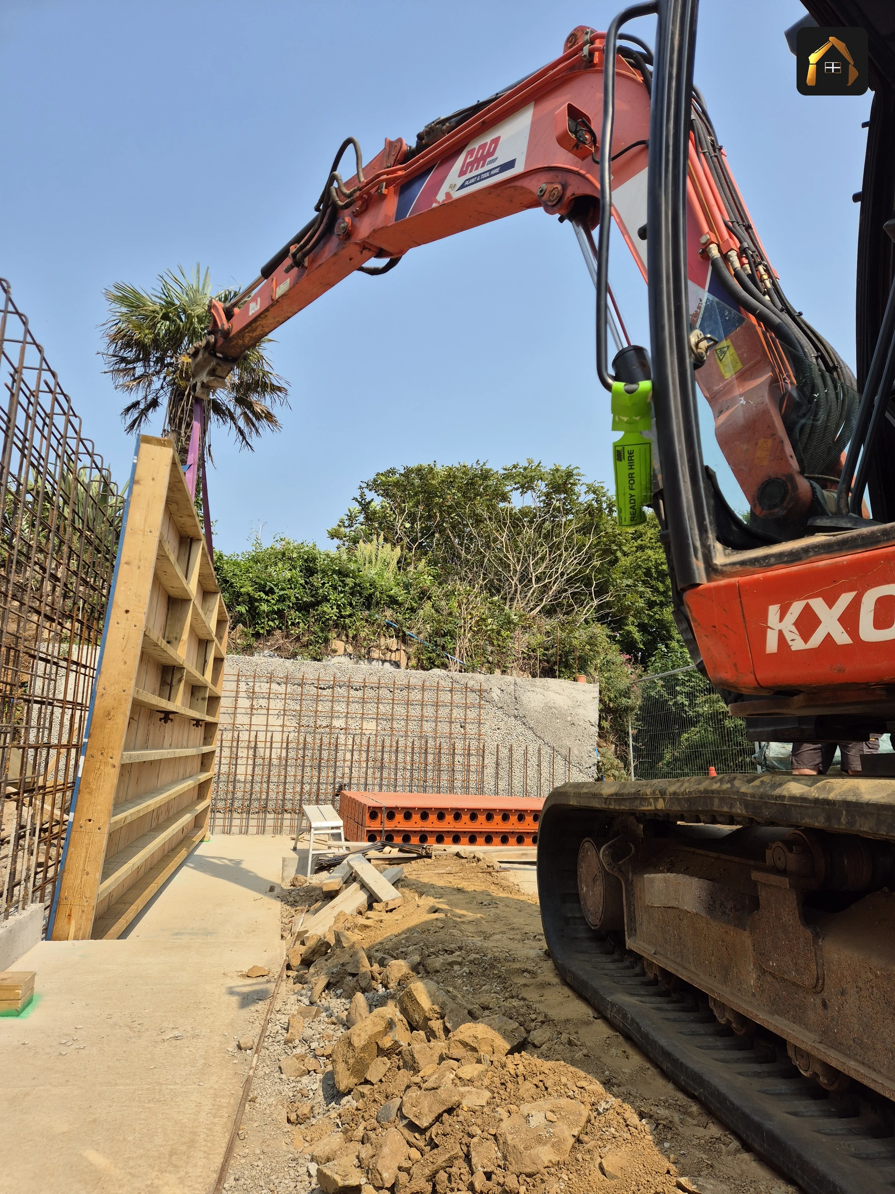 Excavator lifting timber shutter panels into position at Carrick Lodge in St Ives